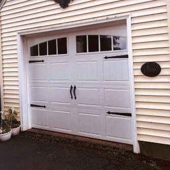 Clopay Bead board short panel garage door with black decorative hardware and arched rectangular windows
