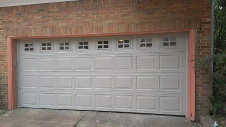 Raised short panel garage door with square windows in Sandstone